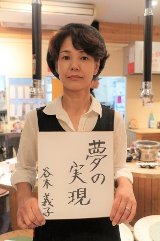 谷本さんが「夢の実現」と書かれた紙を持っている画像