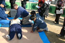 心肺蘇生法を住民が学んでいる写真　子供たちも見よう見真似で練習している