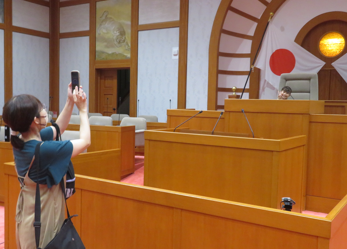 写真：議長席に座って記念写真を撮影する様子
