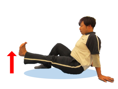 画像：足上げ運動の様子。床に足を伸ばして座り、右足は曲げる。左足の爪先を天井に向け、床から10センチ程度上げている。