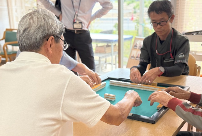 ボランティアの方と三宅さんが一緒に麻雀を打っている写真