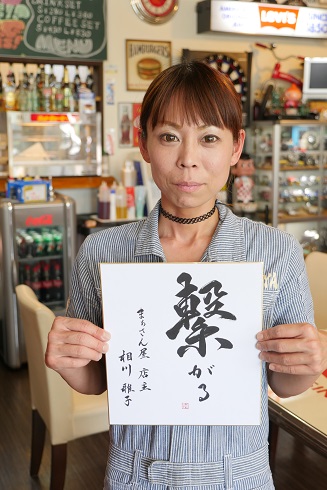 相川さんが「繋がる」と書かれた紙を持った写真