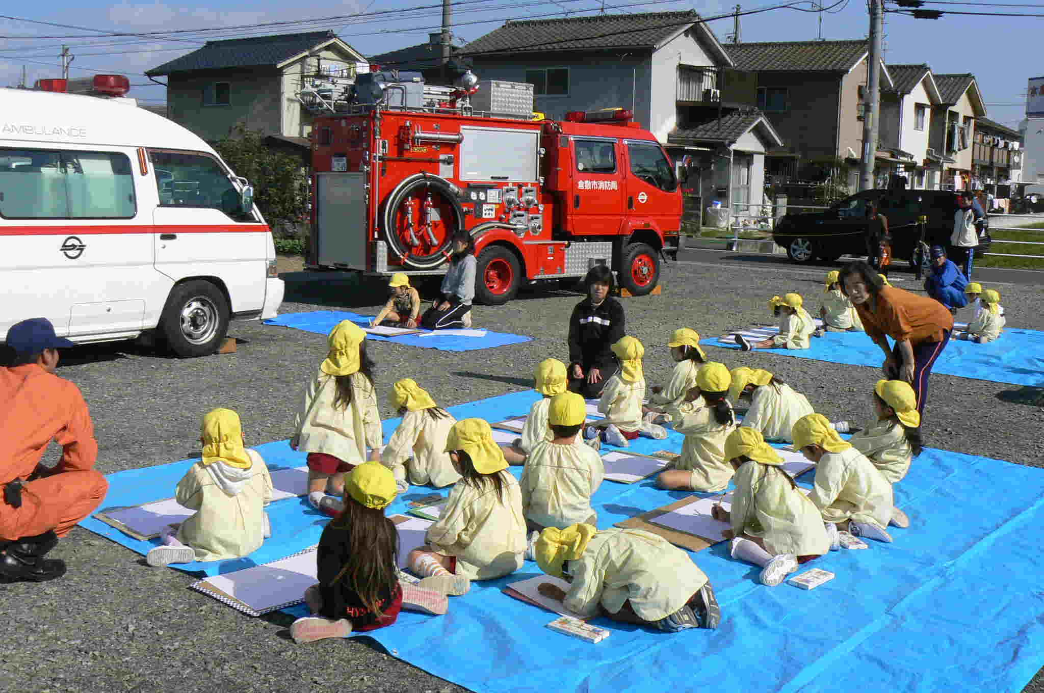 保育園児の写生大会の写真　消防車と救急車を写生している